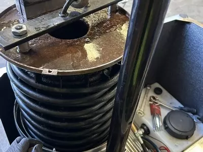 Engineer lifting burst boiler coil out of industrial hot pressure washer during emergency repair in Atherstone.